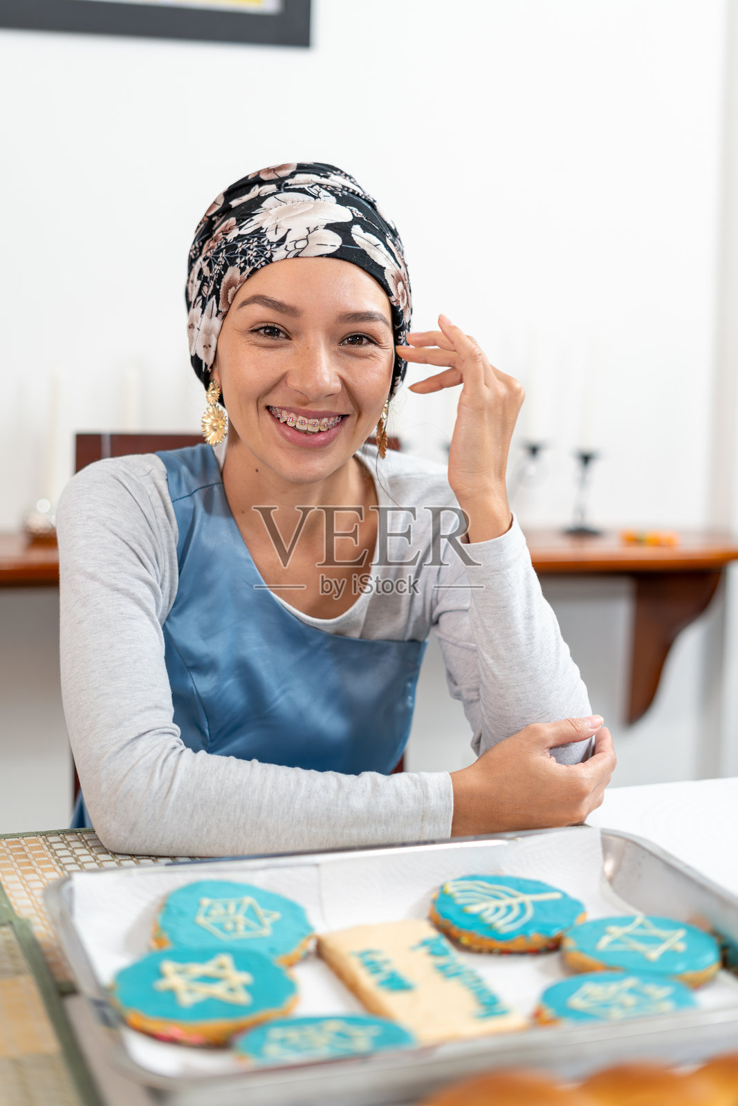 竖版：一位犹太妇女准备在摆满光明节主题饼干的桌子旁庆祝光明节照片摄影图片