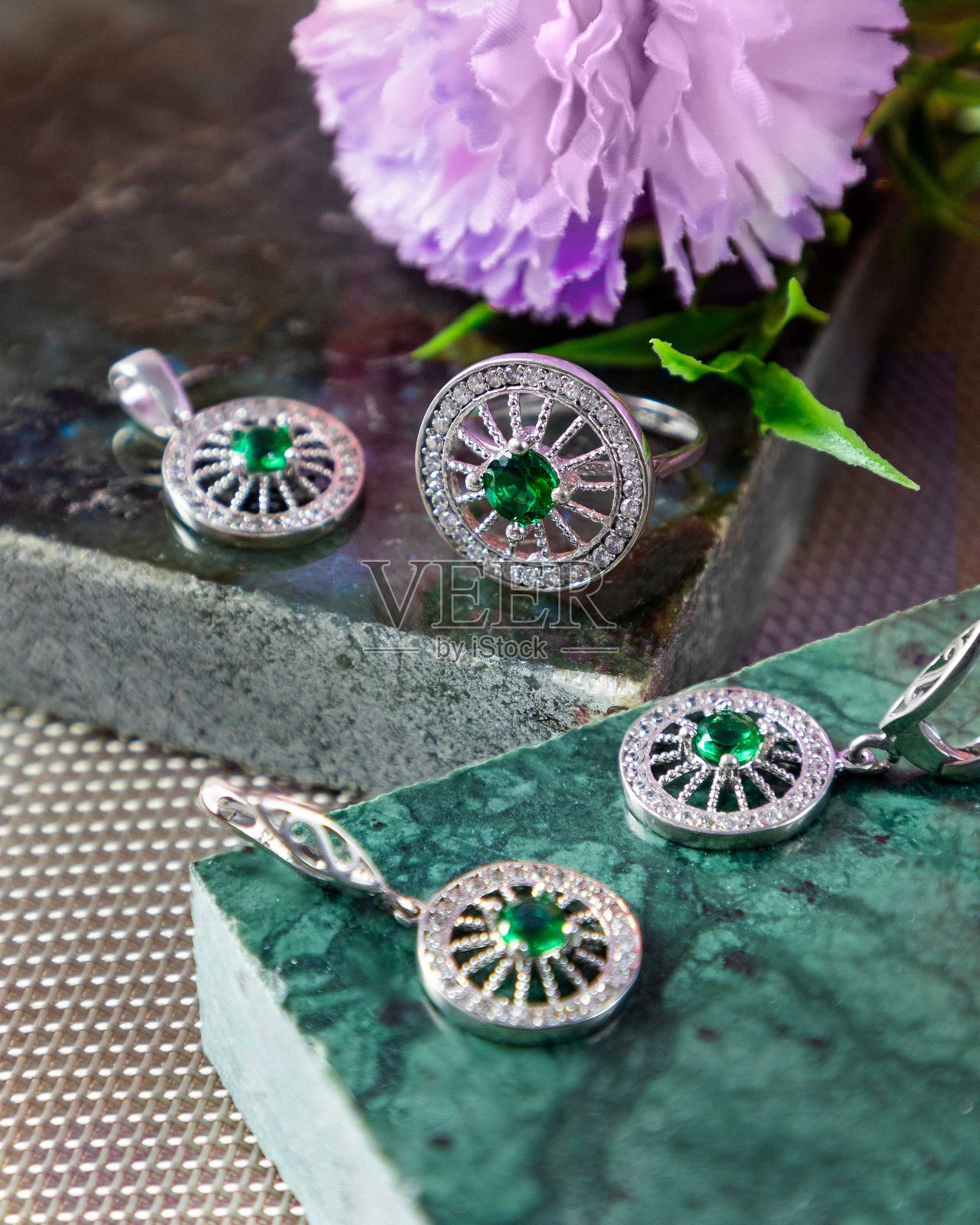 绿大理石背景上的银色珠宝套装，镶嵌有翡翠和钻石照片摄影图片