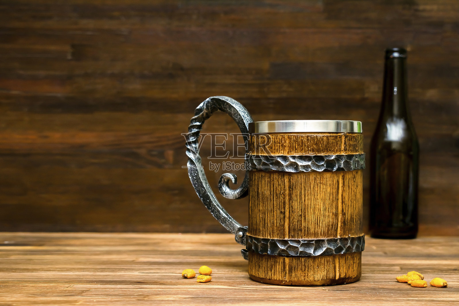 大棕色啤酒杯、麦酒瓶和脆脆的小吃，碱水卷饼、玉米、坚果放在木桌上的碗里，背景特写。酒精鸡尾酒，酒吧饮品，聚会概念，模版，留白。照片摄影图片