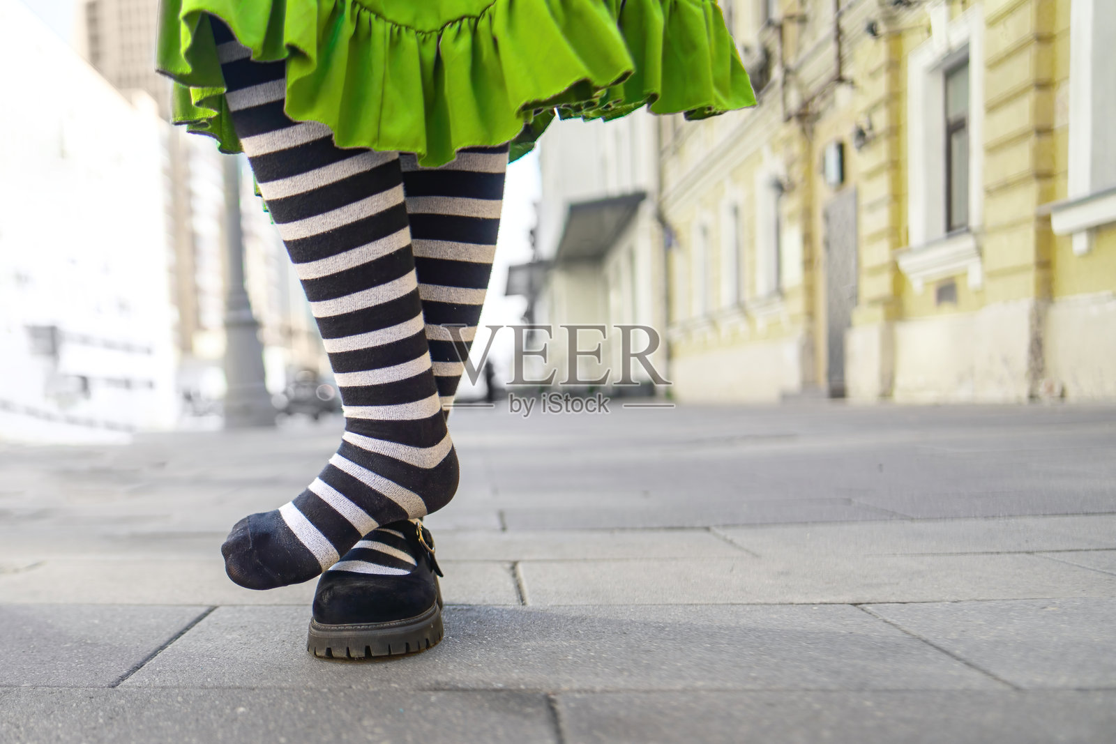 奇幻的场景捕捉到一个女孩穿着条纹袜子，赤脚站在 sidewalk 上，暗示着一个顽皮的时刻或自发的冒险，唤起童年的纯真与自由。照片摄影图片
