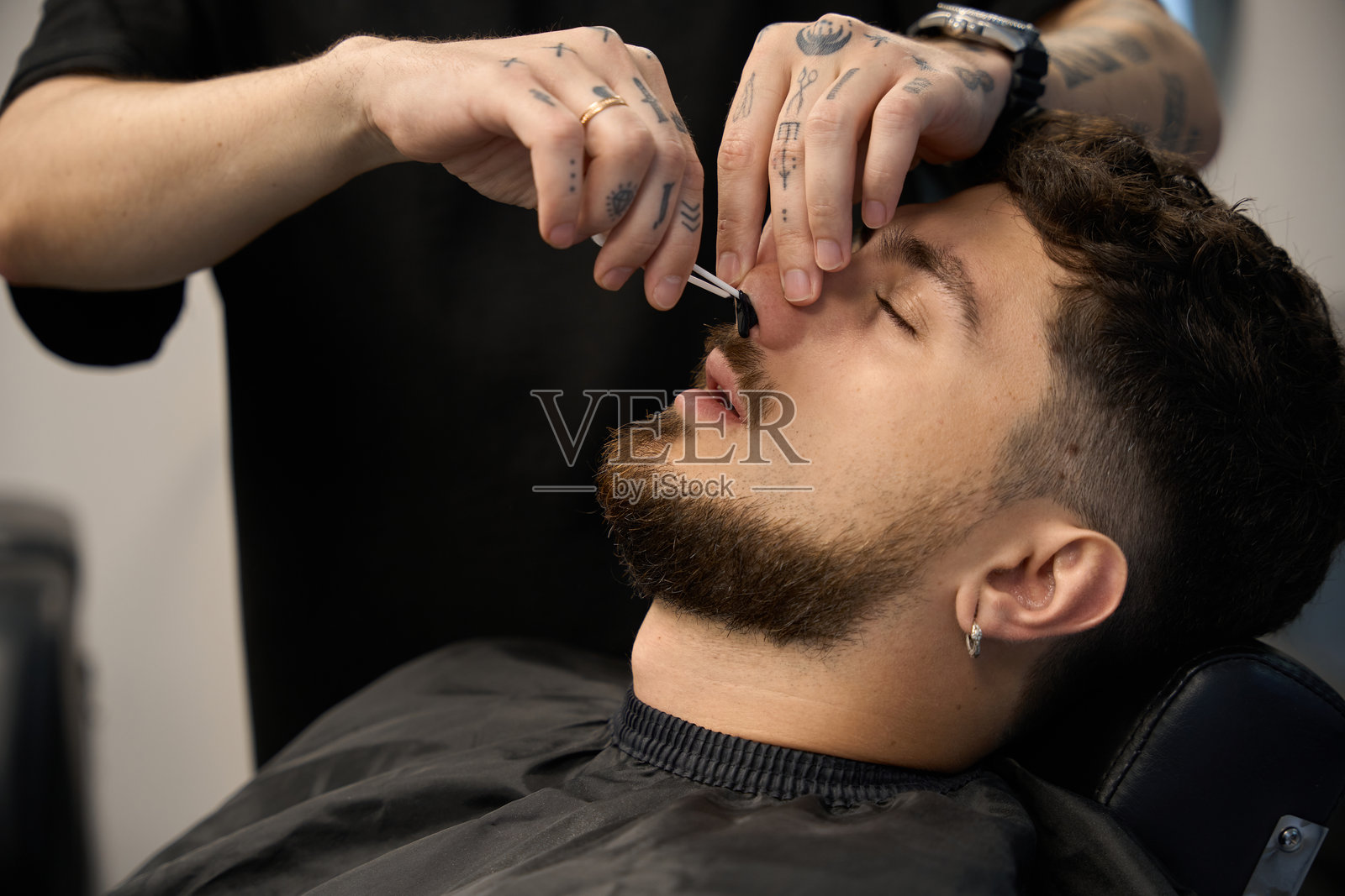 理发师用蜡清理顾客的鼻毛照片摄影图片