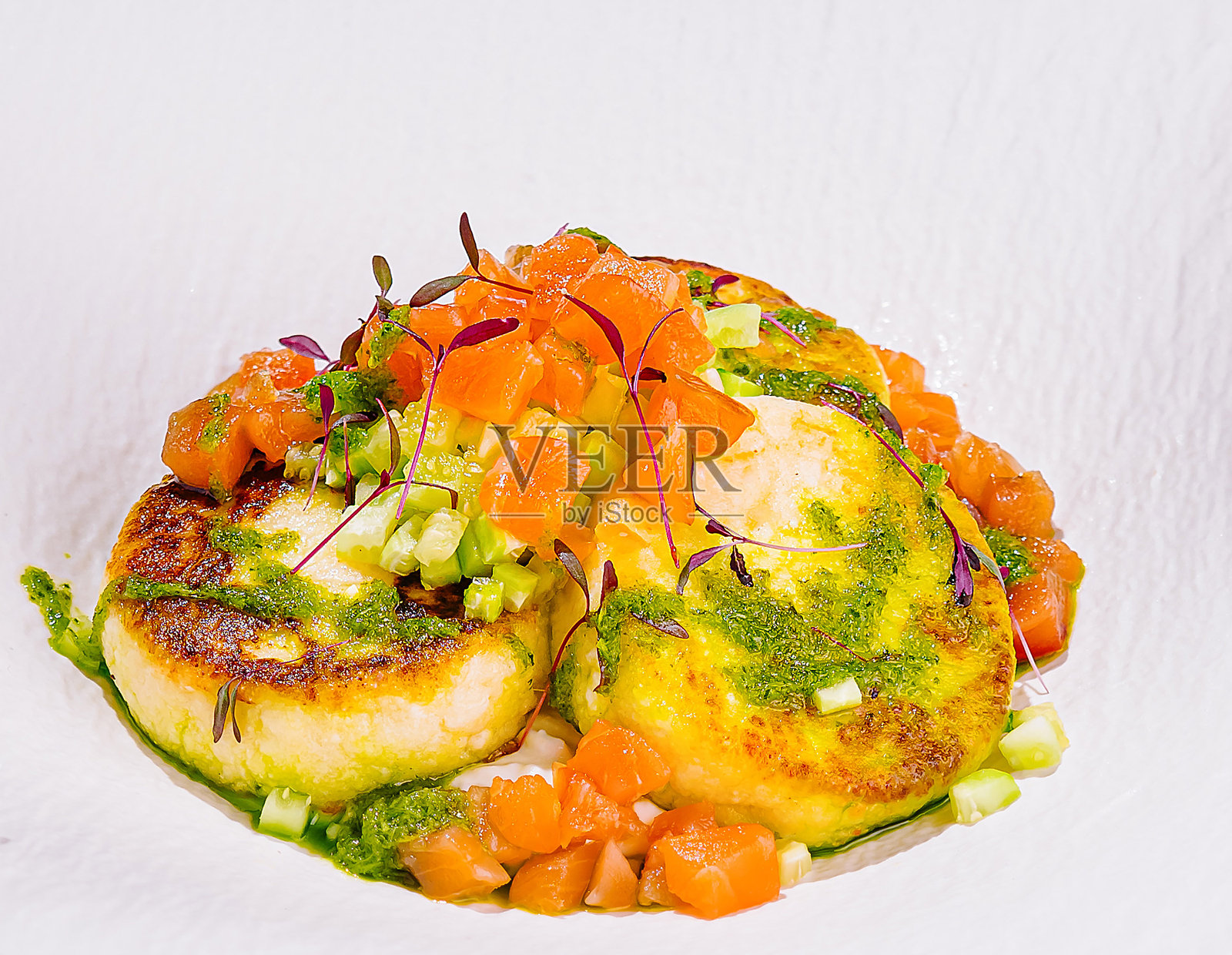 三块炸土豆饼上装饰着微型绿芽和切碎的绿叶。照片摄影图片