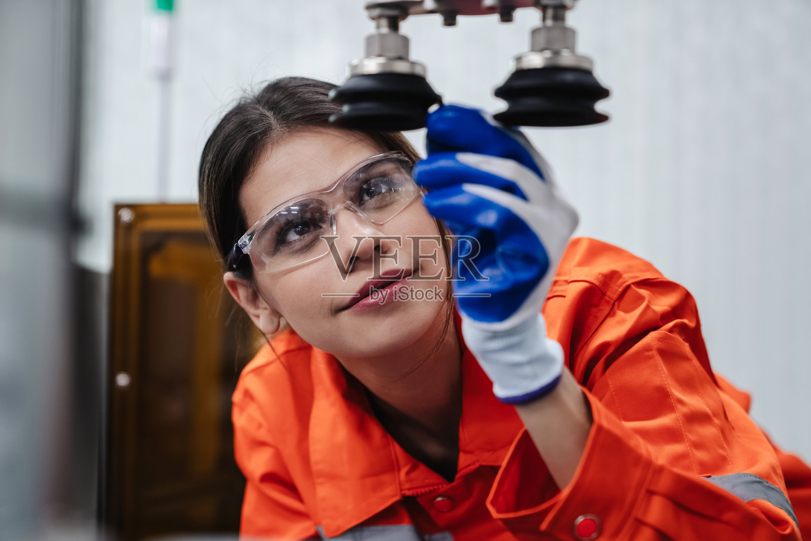 学生工程师在技术工作坊组装机器人手臂。工程师手持机器人控制器，检查机器人手臂的焊接硬件。照片摄影图片