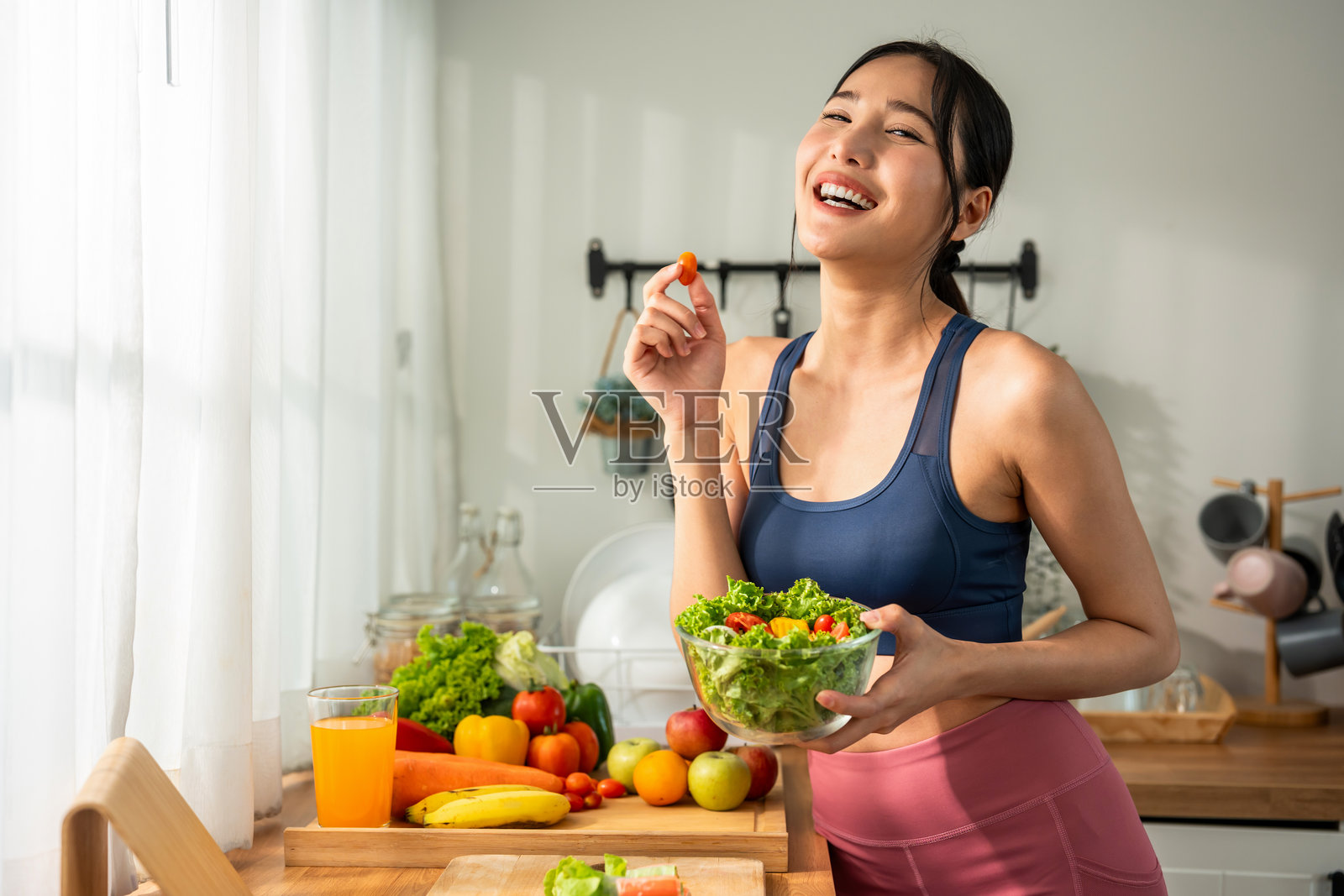 亚洲女运动员在厨房吃绿色沙拉照片摄影图片