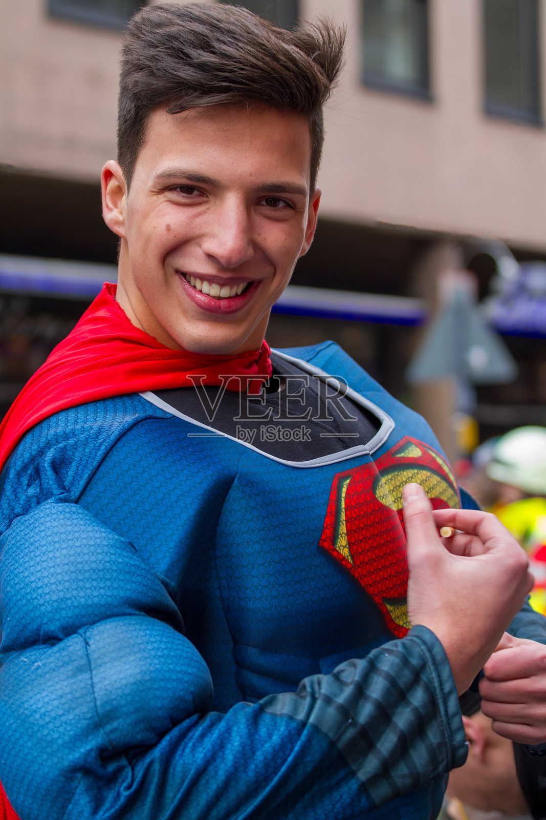 穿着超人服装的头发蓬松的年轻男子照片摄影图片