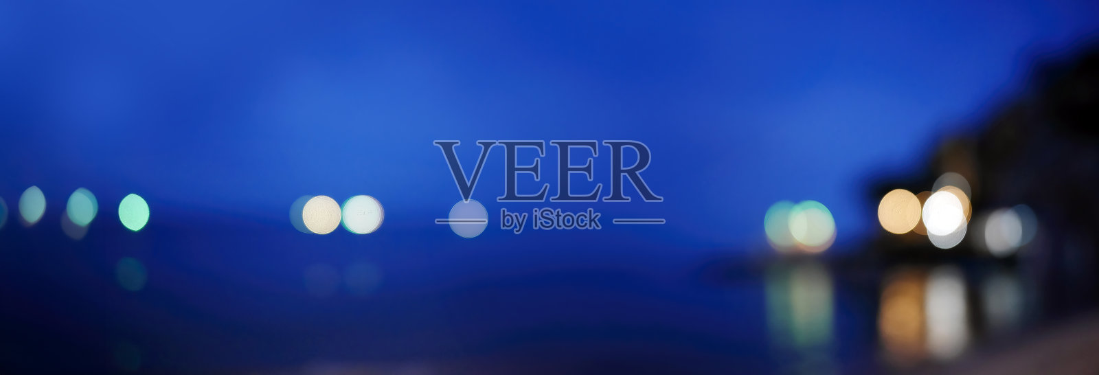 模糊的五彩灯光在黄昏的海洋沙滩背景中，适合作为背景、壁纸或抽象图形概念使用。照片摄影图片