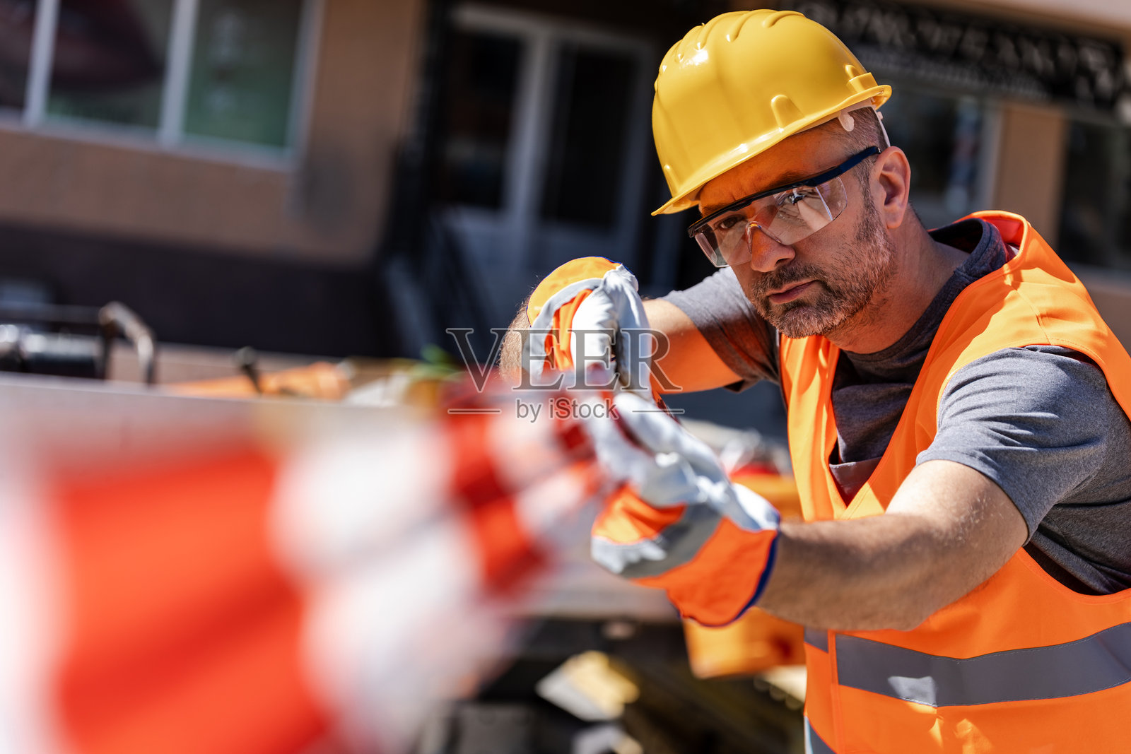 一名建筑工人在阳光明媚的日子里固定安全隔离带。照片摄影图片