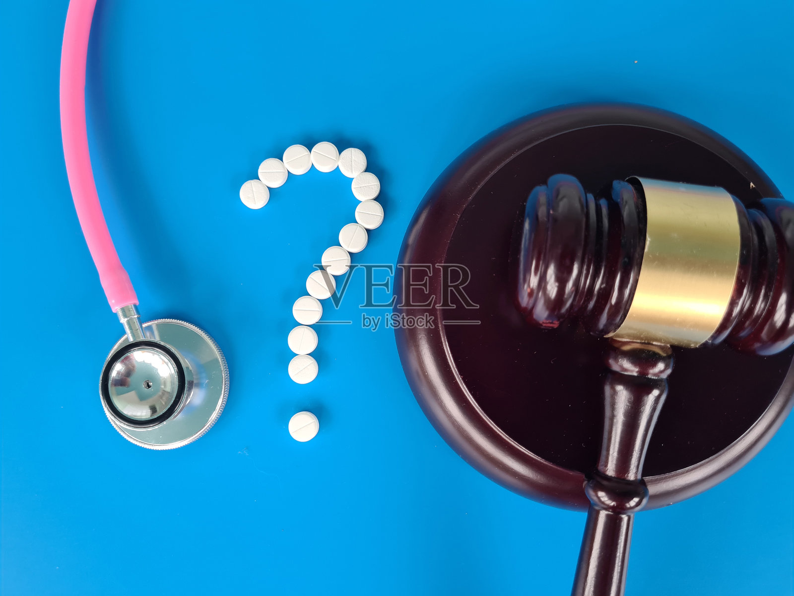 法律与医疗概念：蓝色背景上的法槌、听诊器和药丸，强调医疗保健法律讨论照片摄影图片