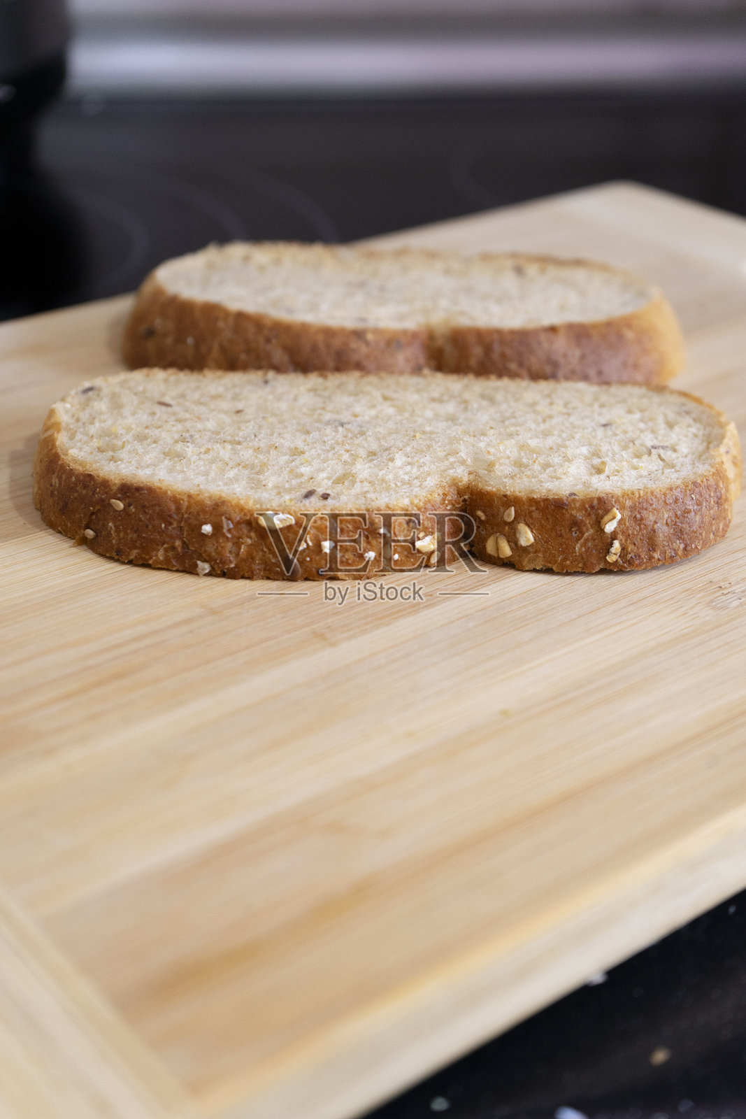 切片面包上撒有芝麻，放在木砧板上。照片摄影图片