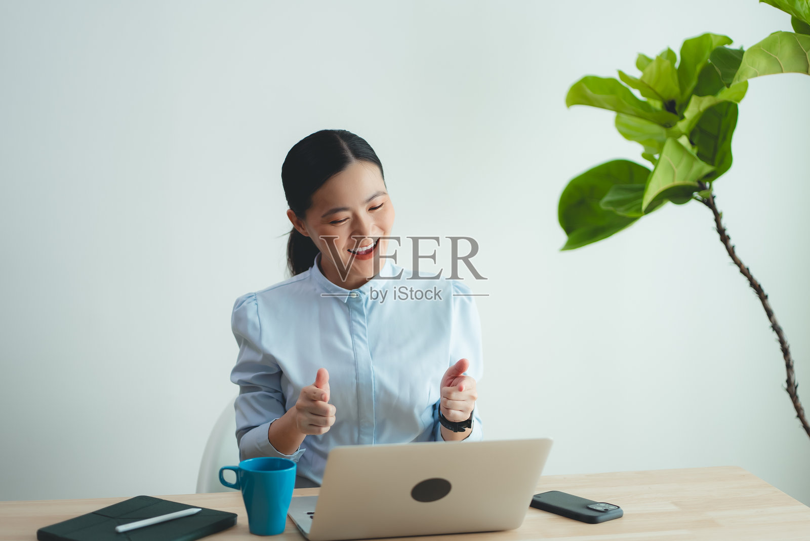 在家办公的亚洲女人使用笔记本电脑，感到高兴和兴奋，并做出胜利的手势照片摄影图片