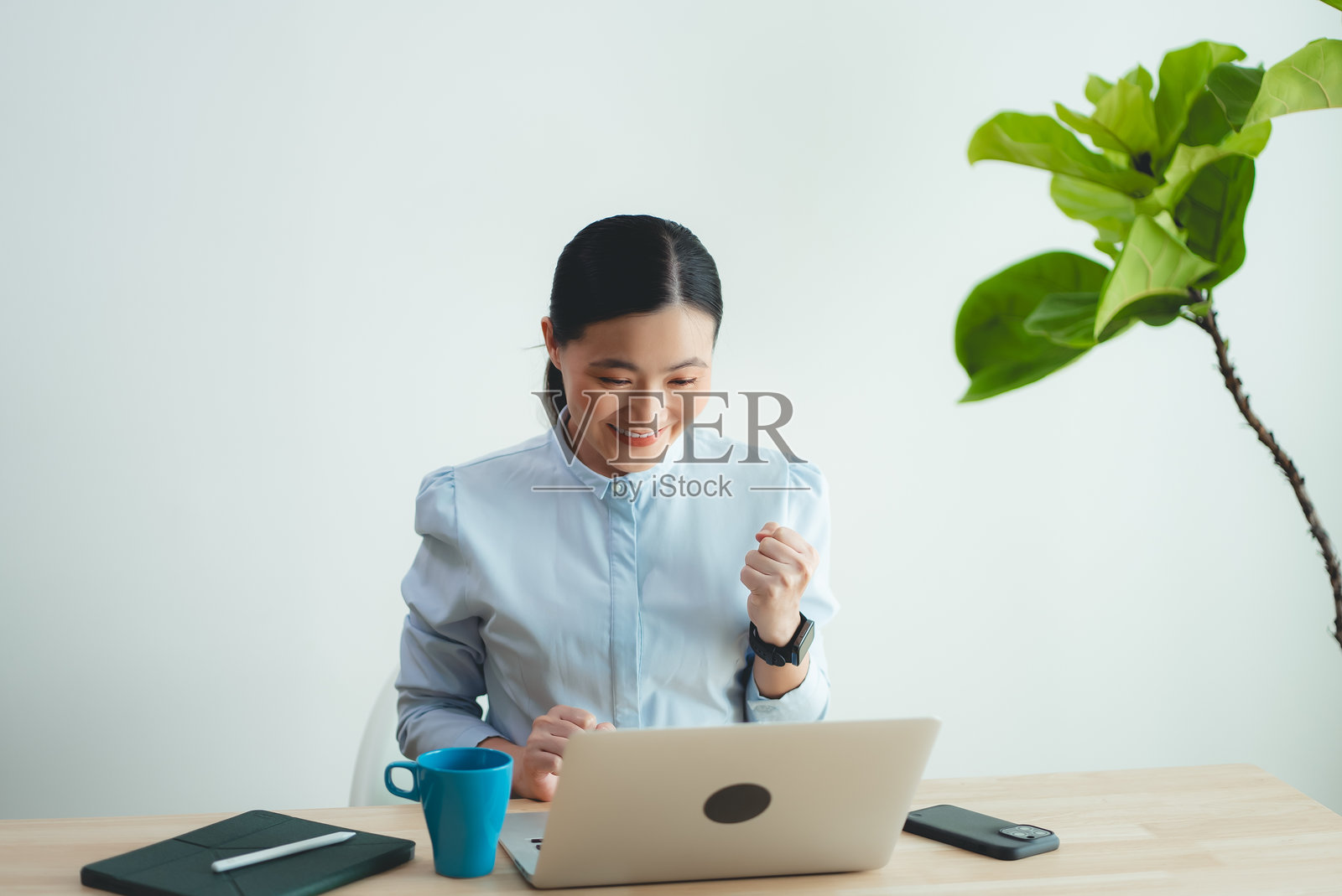 在家办公的亚洲女人使用笔记本电脑，感到高兴和兴奋，并做出胜利的手势照片摄影图片