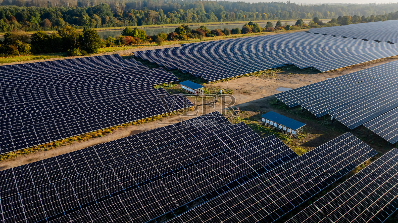 基尔运河沿岸的工业太阳能发电站，展示了太阳能组件和白色汇流箱阵列，以及用于连接太阳能系统电网的电力电缆。照片摄影图片