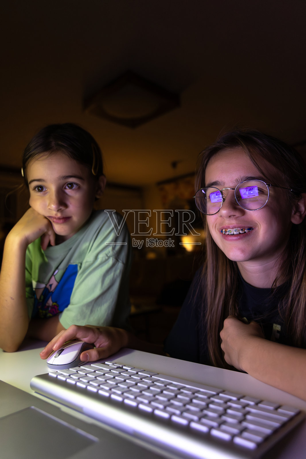 两个年轻女孩在夜晚使用电脑。照片摄影图片