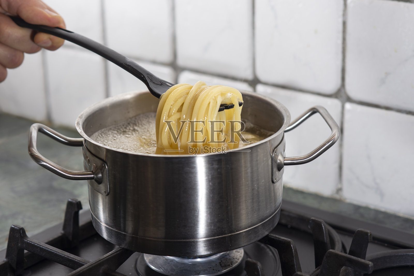 烹饪时处理锅中的意大利面照片摄影图片