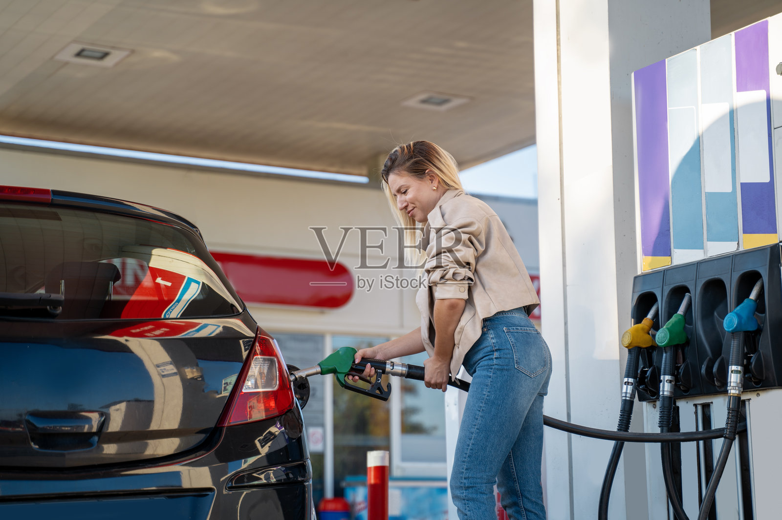 年轻迷人的金发女性独自给汽车加油照片摄影图片