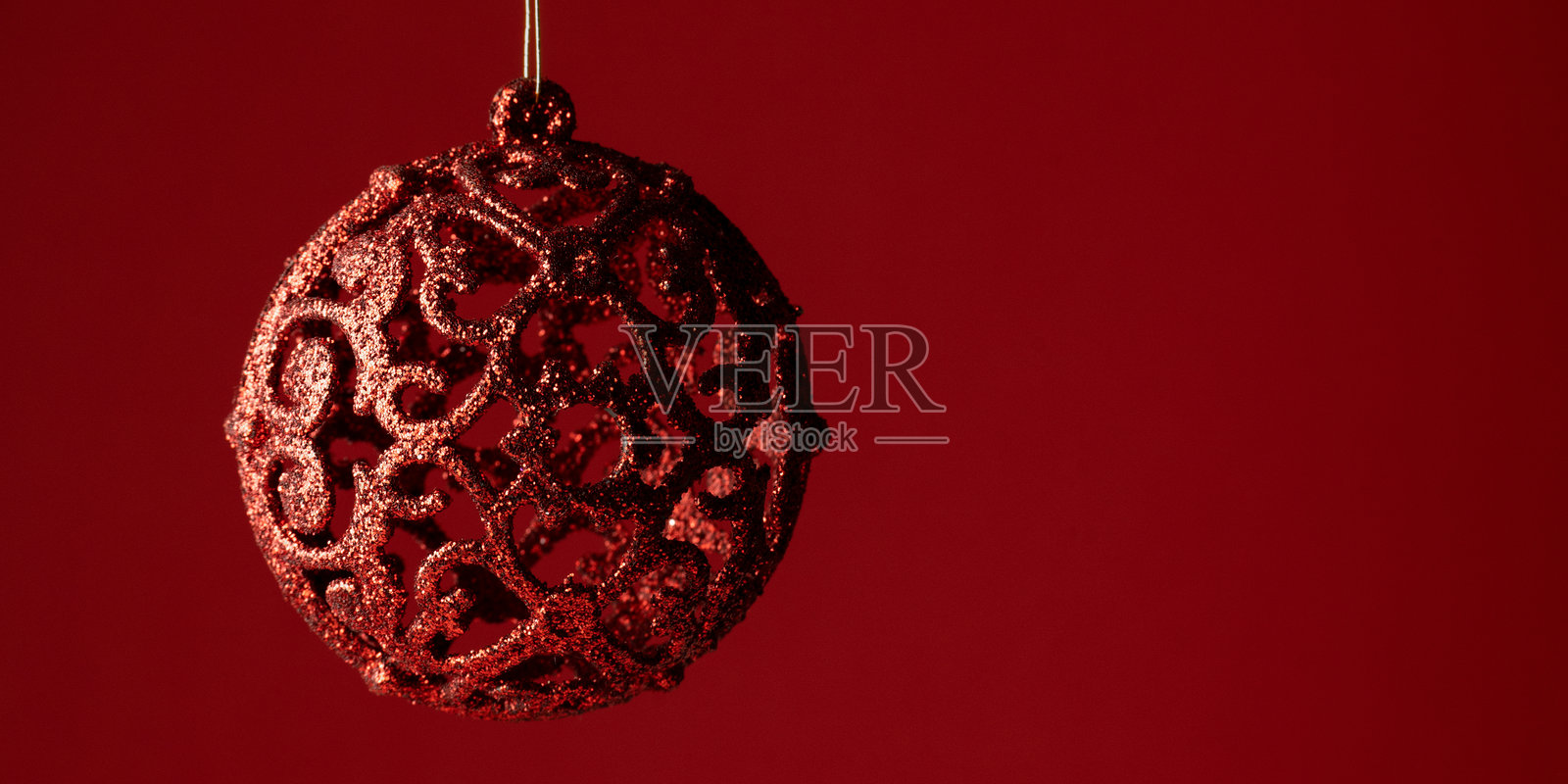 圣诞节简约装饰背景，皇家红色背景上有一个天鹅绒球装饰，留有文字空间照片摄影图片