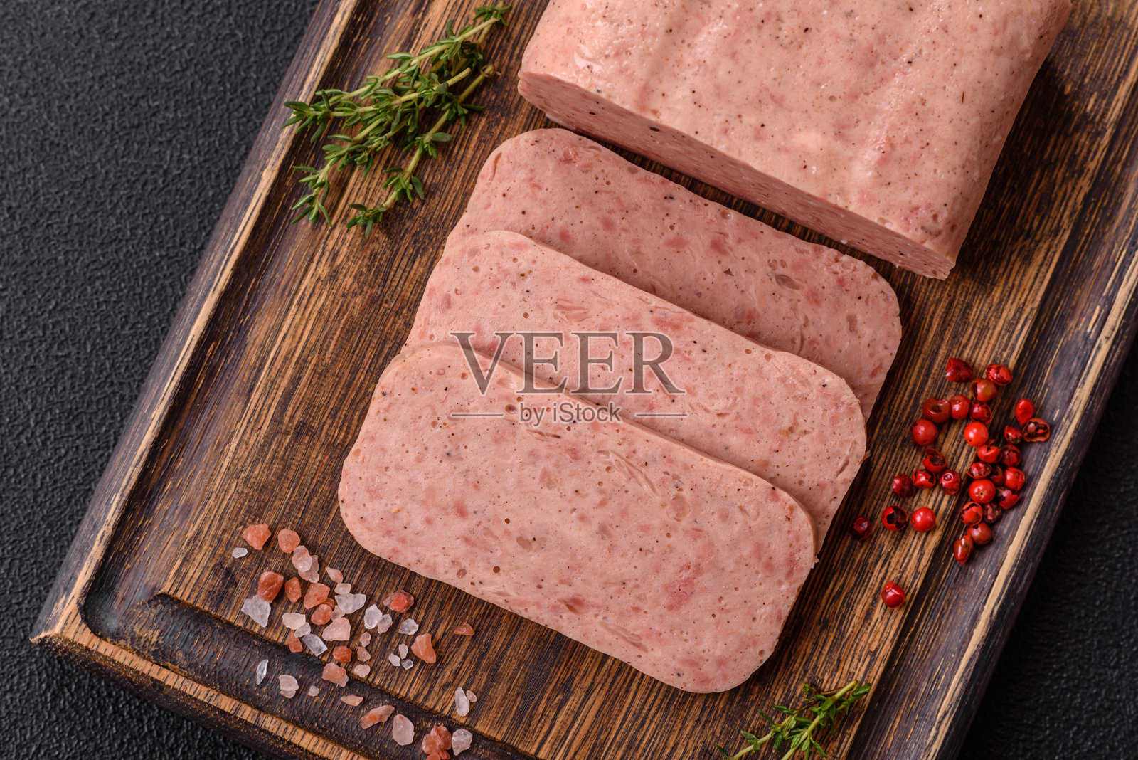 美味的罐装粉色香料火腿或午餐肉，配有盐、香料和草药照片摄影图片