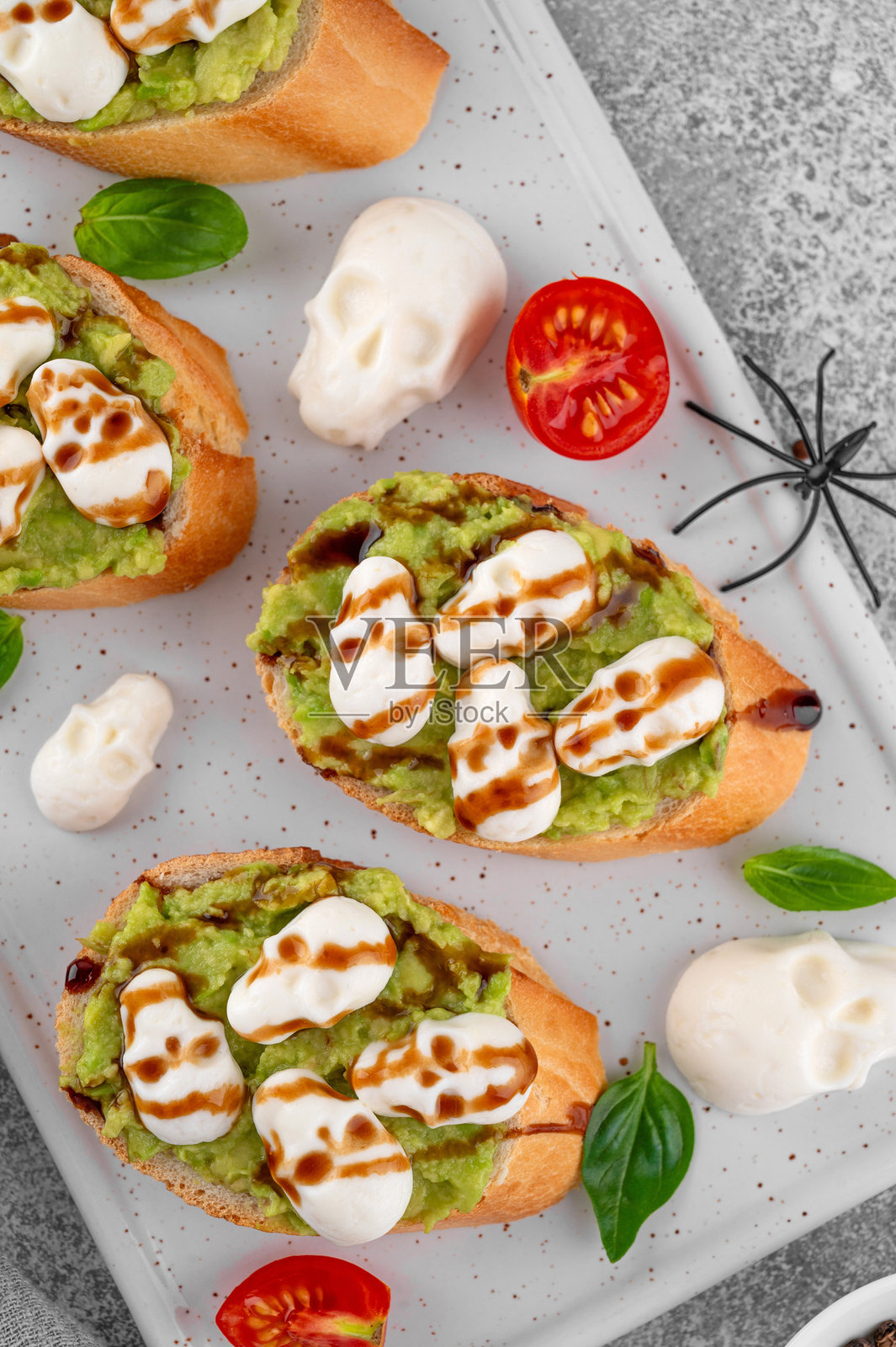 万圣节食品。鳄梨吐司，上面放着骷髅形状的马苏里拉奶酪，淋上香醋酱。搞笑的食品创意。俯视图，留白空间。照片摄影图片