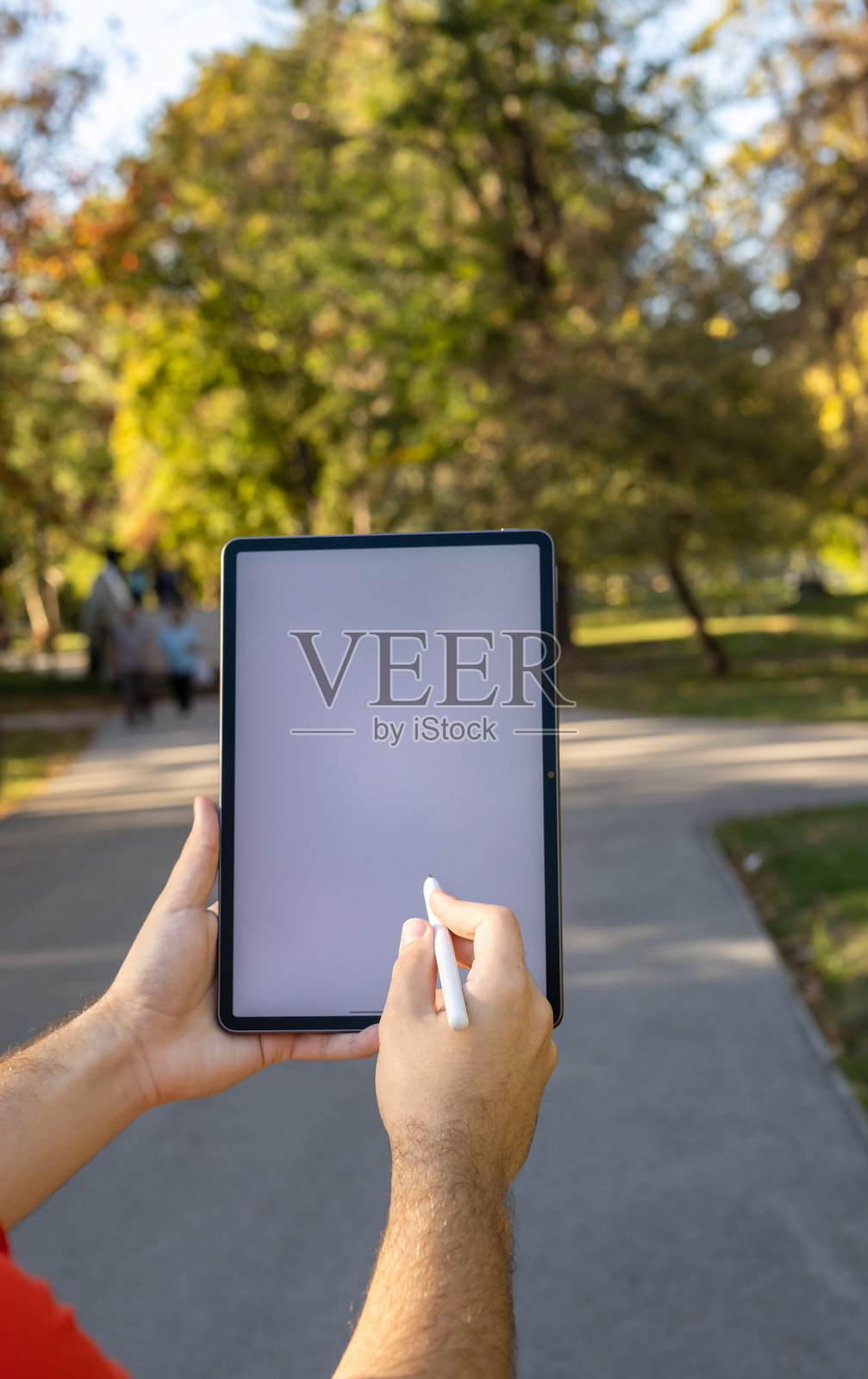 年轻大学生在公园户外使用带触控笔的空白屏幕平板电脑照片摄影图片