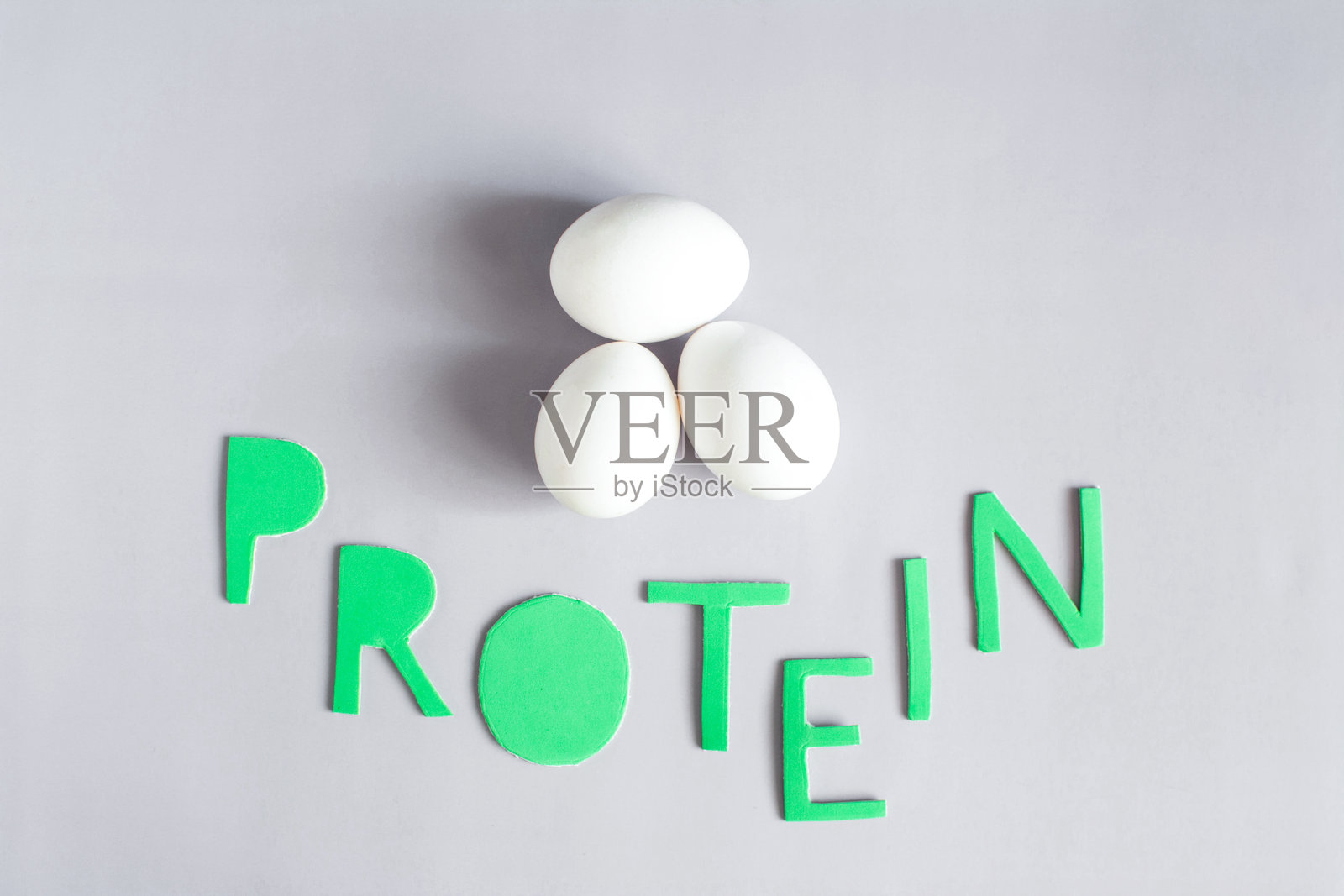 三个大鸡蛋，浅色背景上彩色字母写着“蛋白质”照片摄影图片