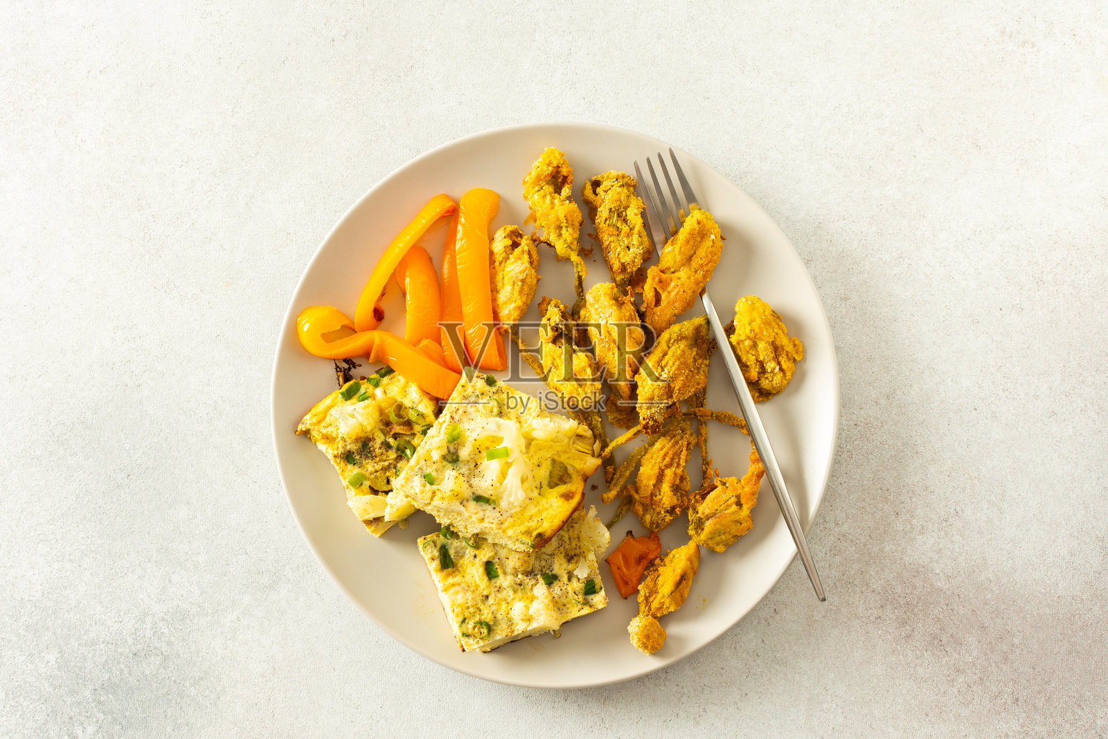 享受酥脆的炸西葫芦花、香浓的花椰菜煎蛋卷配炖辣椒，以及色彩鲜艳的新鲜混合绿叶沙拉，带来一顿健康营养的美餐。照片摄影图片