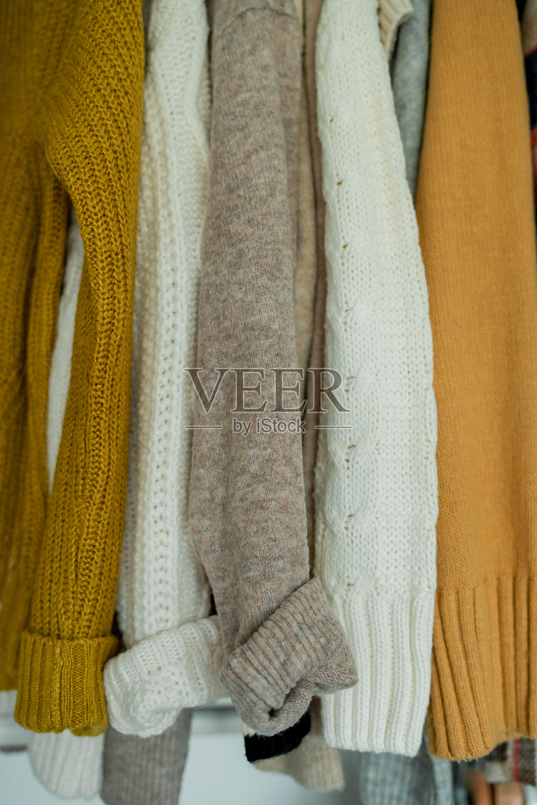 温暖的秋季衣物在衣柜中编织。家庭整理。照片摄影图片