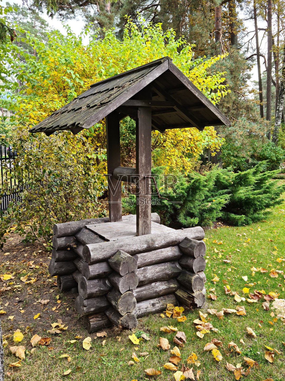 村庄边缘的一口古老木制水井，顶部有坚固的屋顶照片摄影图片