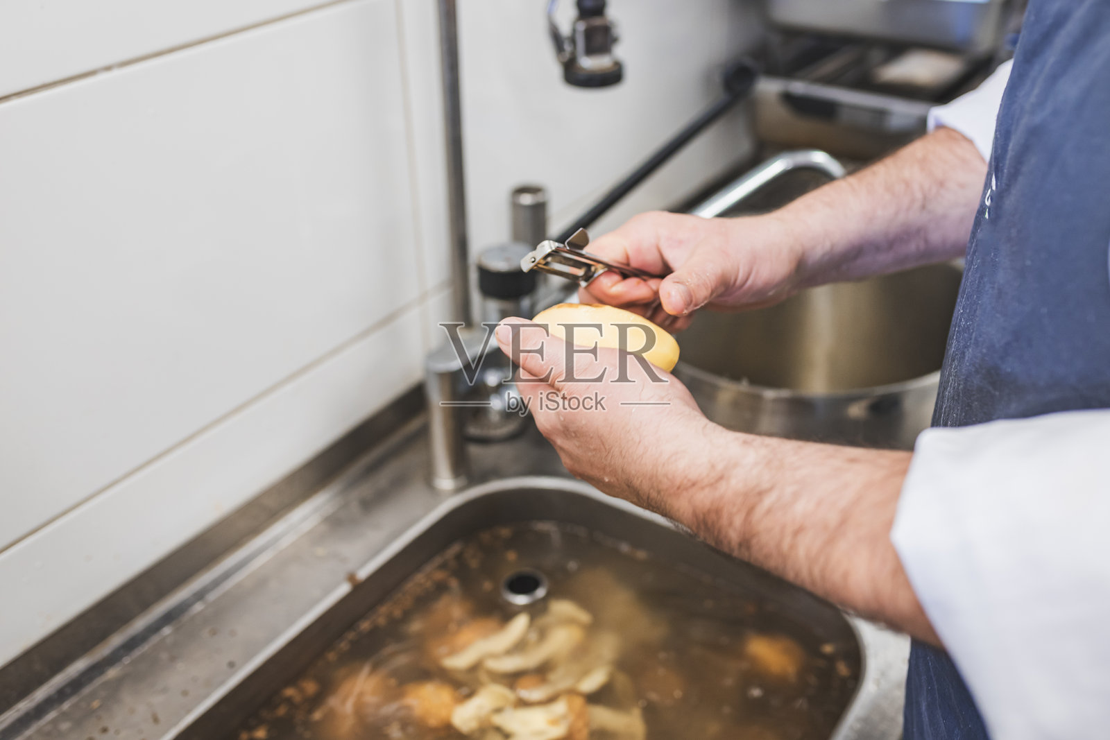 专业厨房中厨师剥土豆的特写镜头照片摄影图片