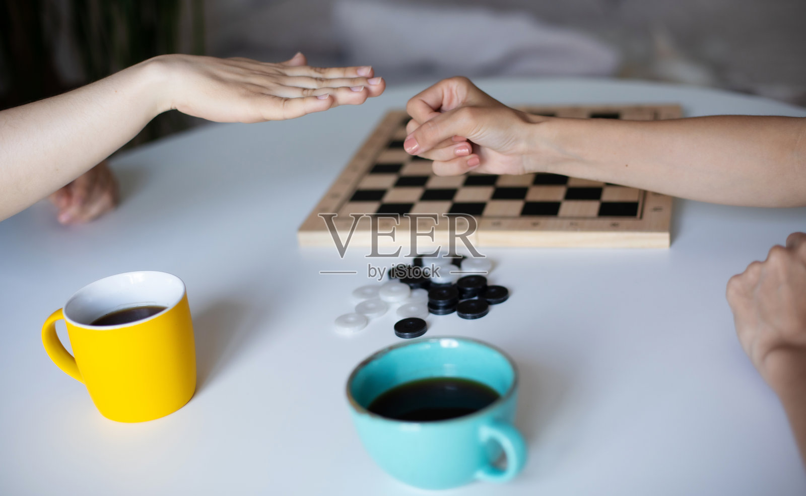 两人在玩跳棋，专注嬉戏动作，桌上有咖啡杯照片摄影图片