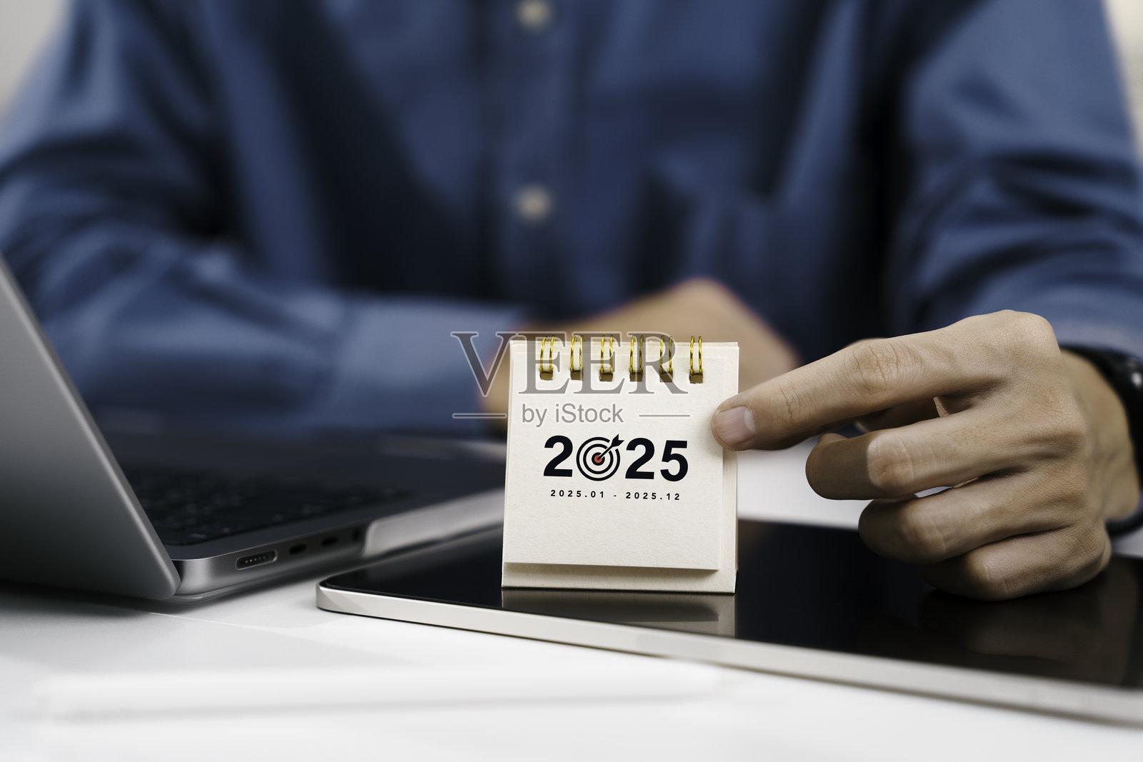 商人将2025年新年快乐日历放在桌子上，象征着新年的开始。决心、目标、计划和行动的概念。目标规划和年度及财务任务。照片摄影图片