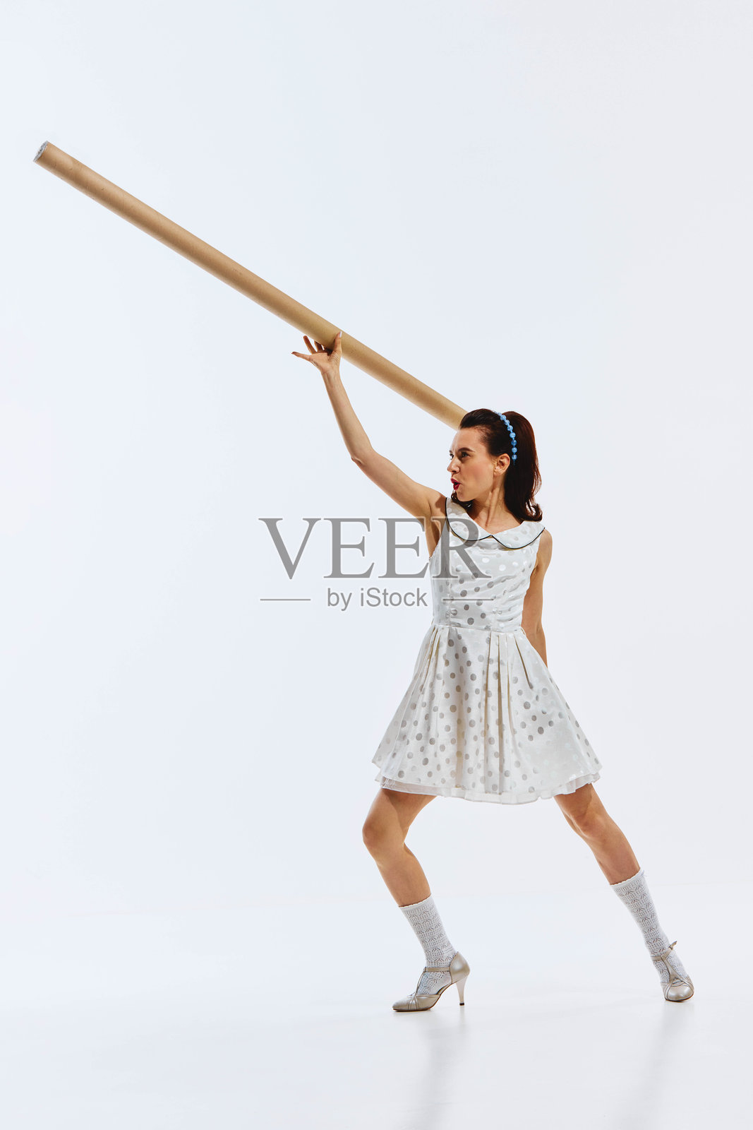 身穿波点连衣裙，手拿纸筒，充满活力的女性，展现积极情绪。新的开始，启程，创业启动照片摄影图片