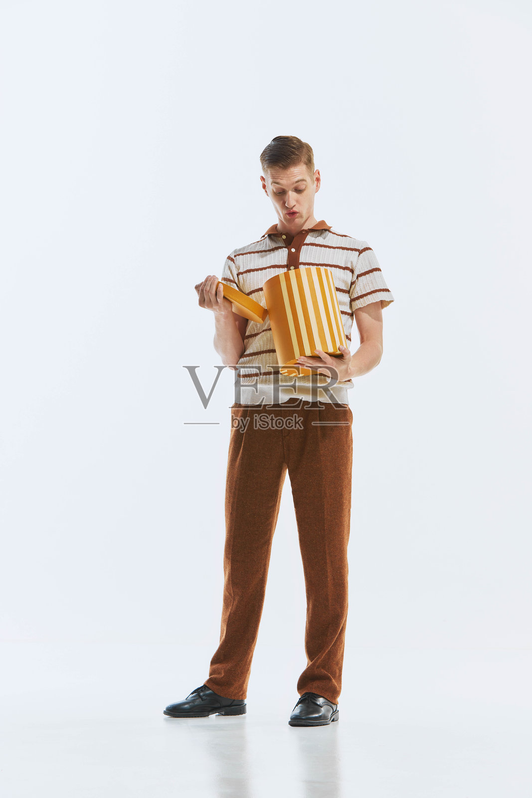 身穿复古服装的时尚青年打开纸板礼品盒，脸上露出惊喜的表情照片摄影图片