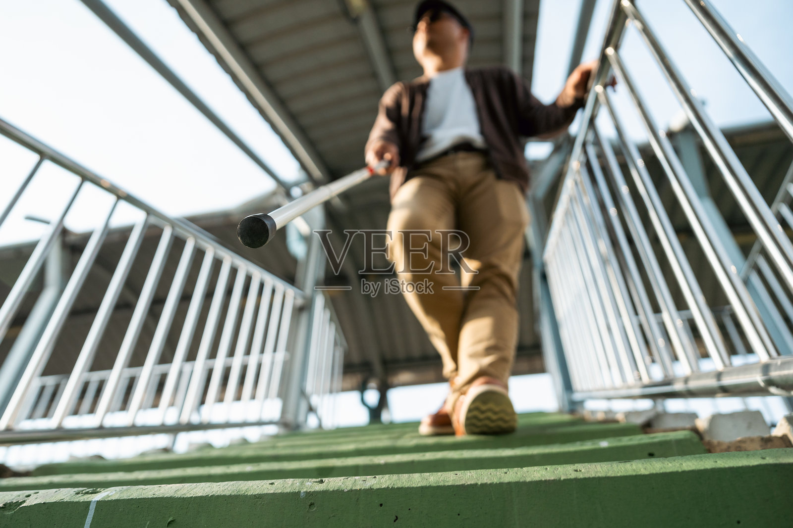 年轻盲人拄着拐杖在城市里行走照片摄影图片