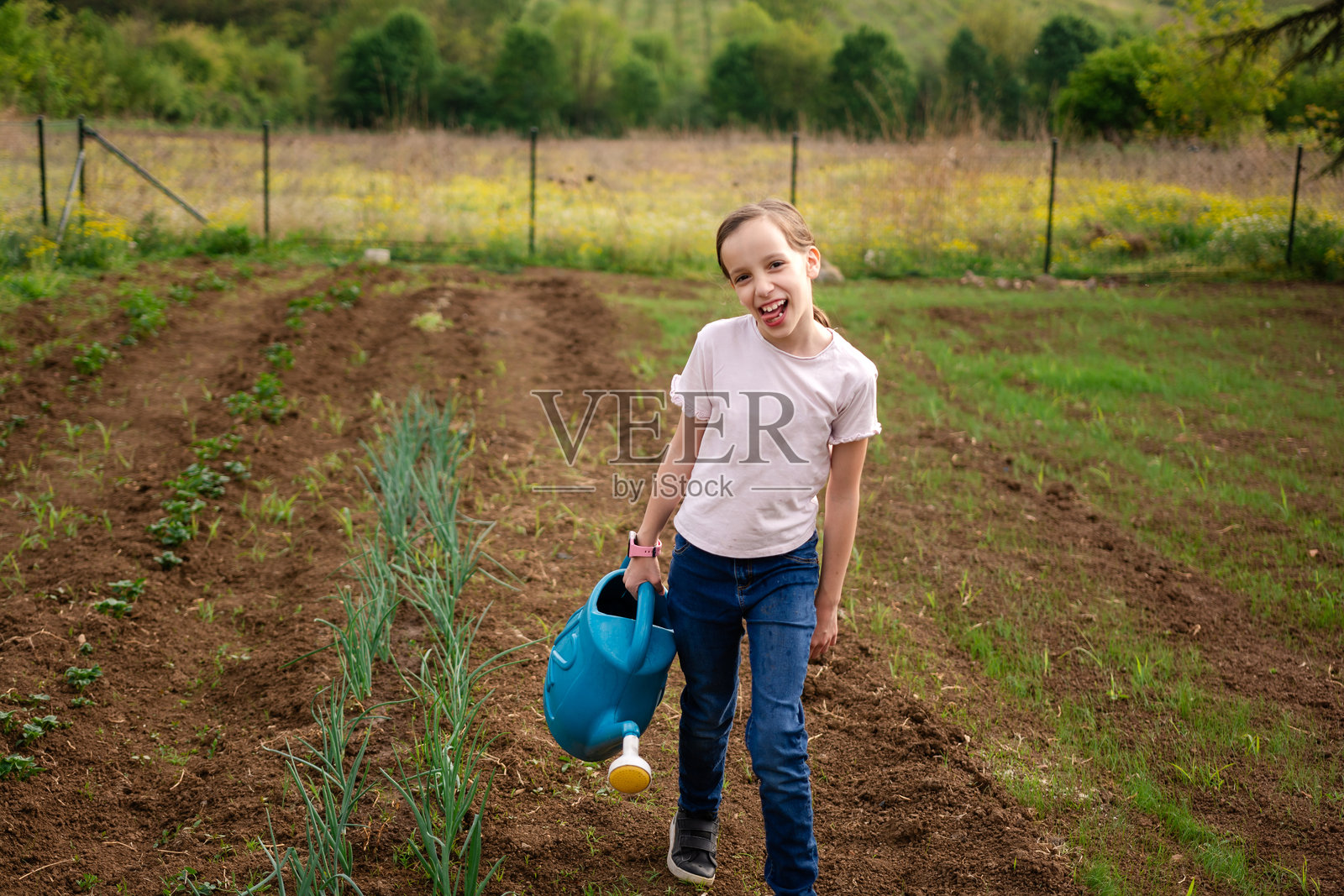 在花园里提水壶的女孩照片摄影图片