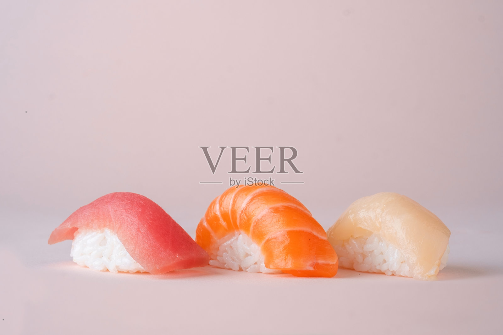 粉色背景上的三文鱼、金枪鱼和鲈鱼寿司拼盘照片摄影图片