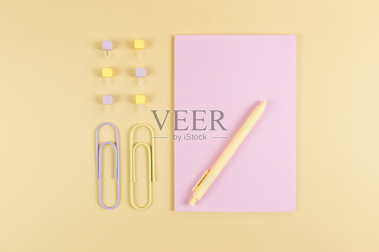 黄色背景上的粉色笔记本顶视图，回形针、笔和图钉，学校、办公室壁纸照片摄影图片