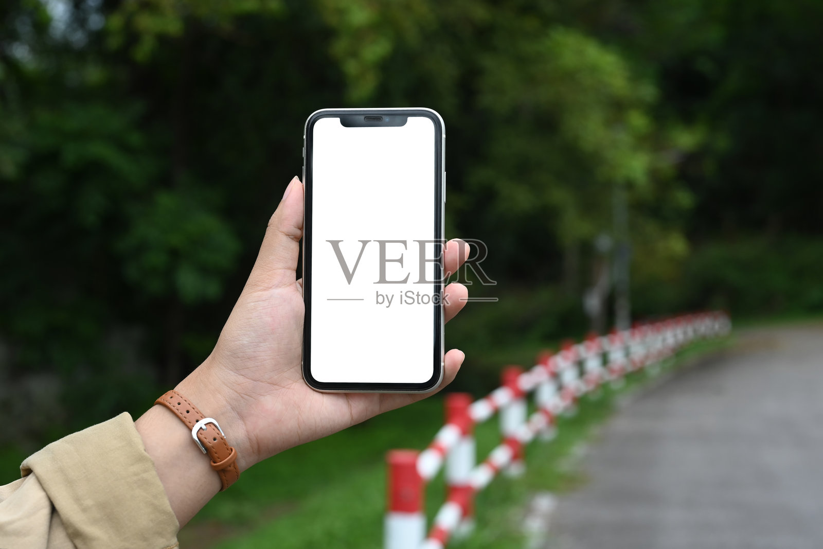 女人在绿树和道路的户外背景下拿着智能手机照片摄影图片