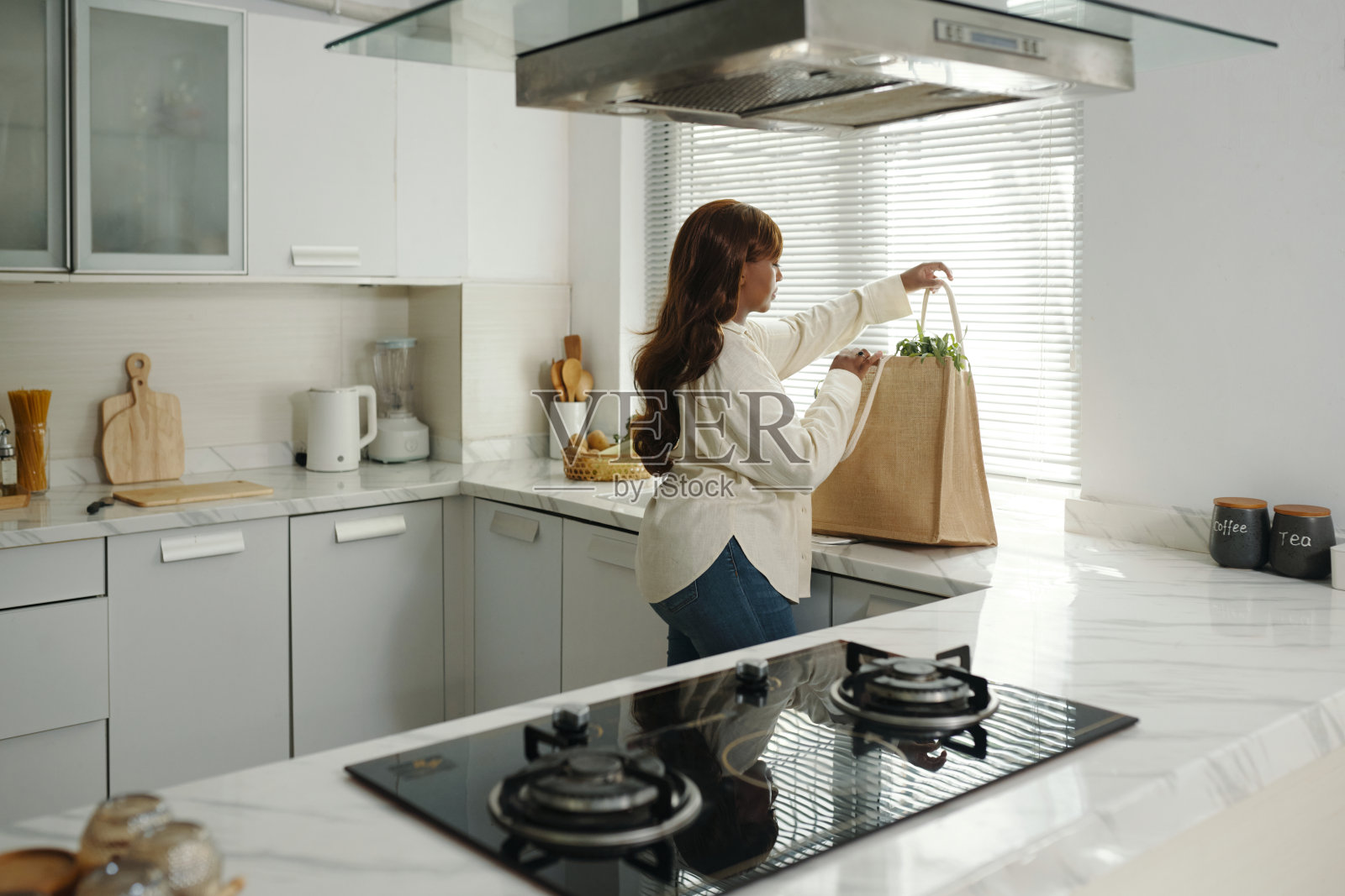 女性在现代白色厨房中整理杂货照片摄影图片