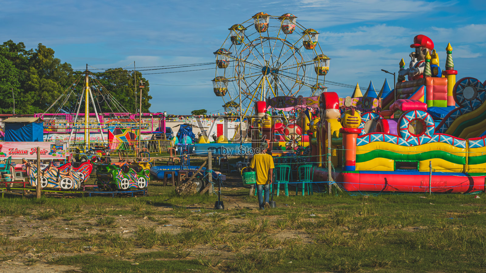 一位街头小贩正在夜市游乐场进入儿童游乐区。照片摄影图片