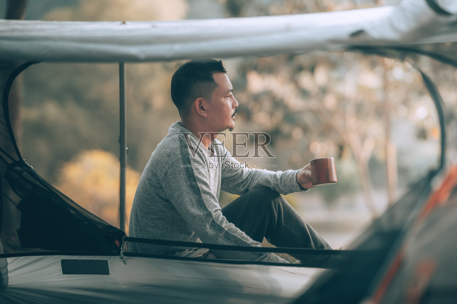 男人在假期的森林露营旅行中早晨喝咖啡。度假和旅行概念。照片摄影图片