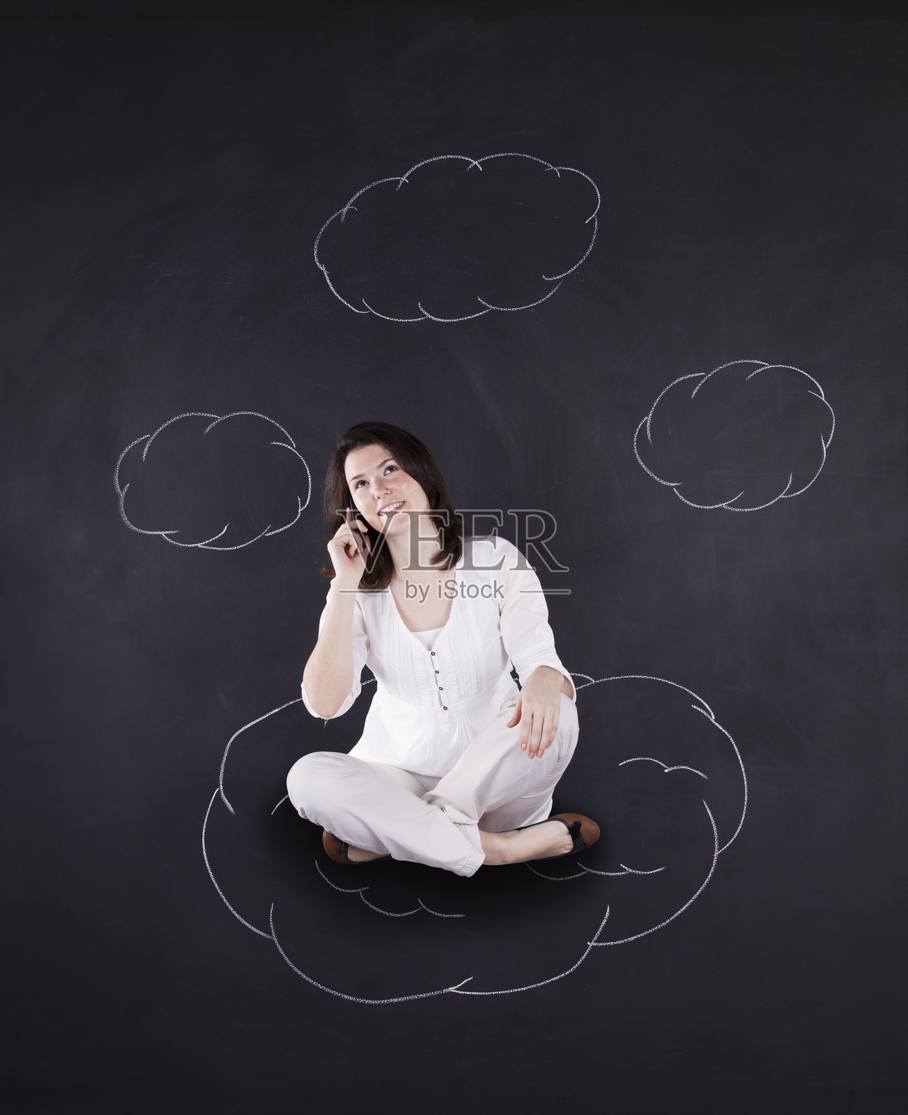 悬浮在黑板旁的商务女性，黑板上装饰着异想天开的云朵照片摄影图片