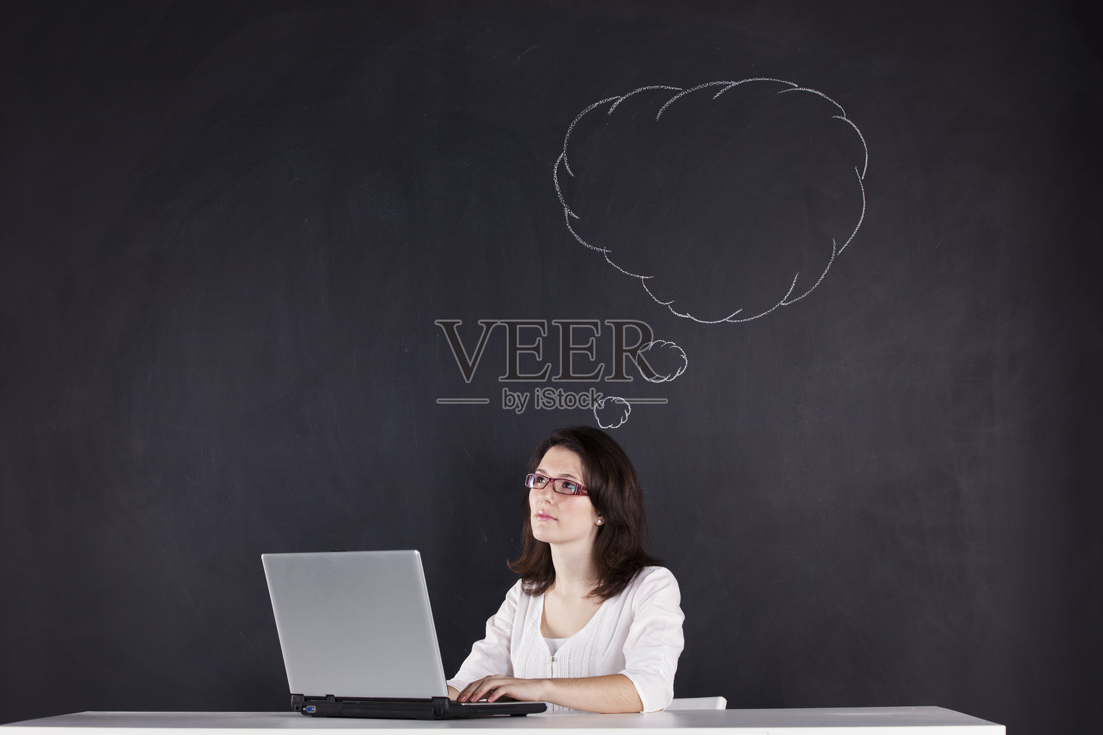 女商人认真地在装饰有象征图像的黑板旁工作照片摄影图片