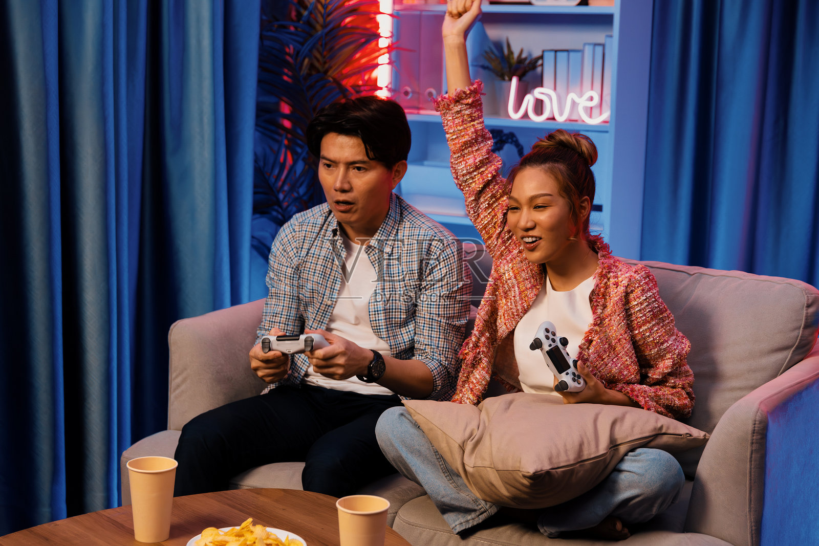 情侣用游戏杆玩游戏，女人举起拳头获胜照片摄影图片