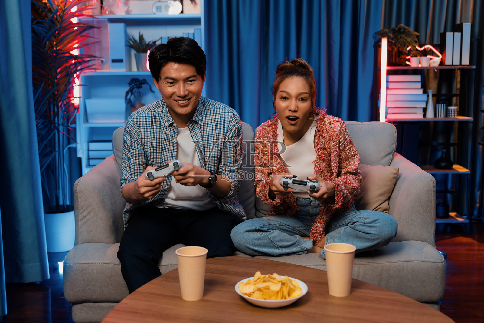 微笑情侣在零食前用操纵杆玩电子游戏照片摄影图片
