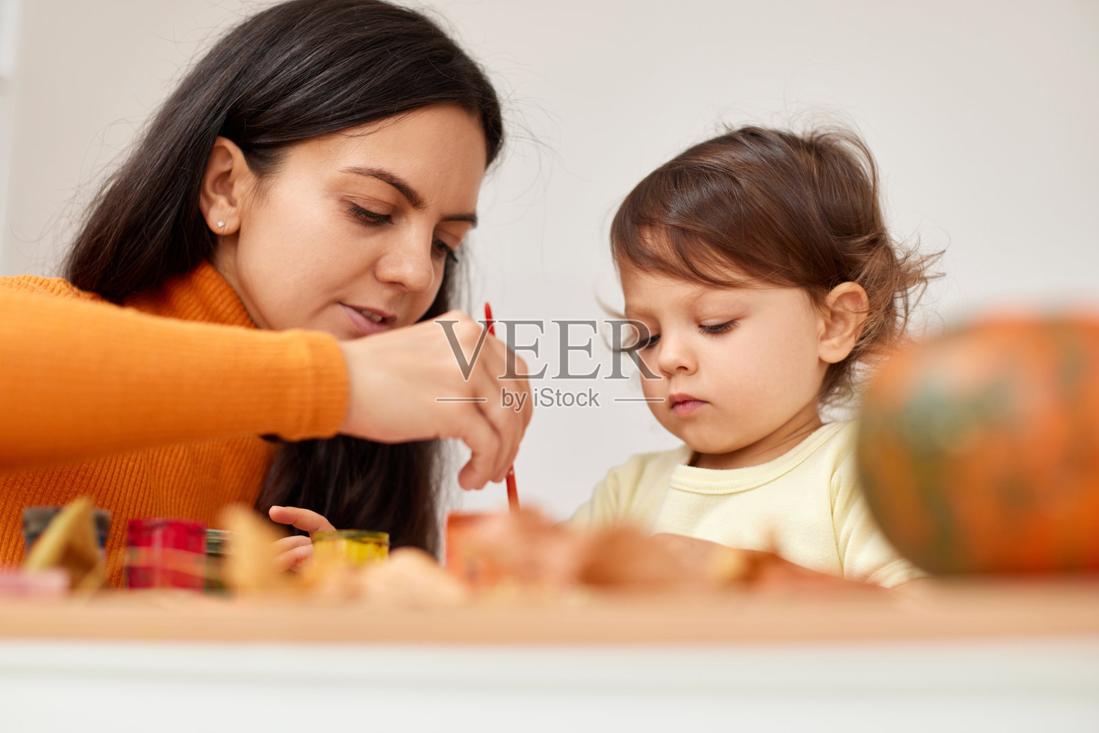 快乐的小女孩和她的妈妈在为秋季假期绘画。照片摄影图片