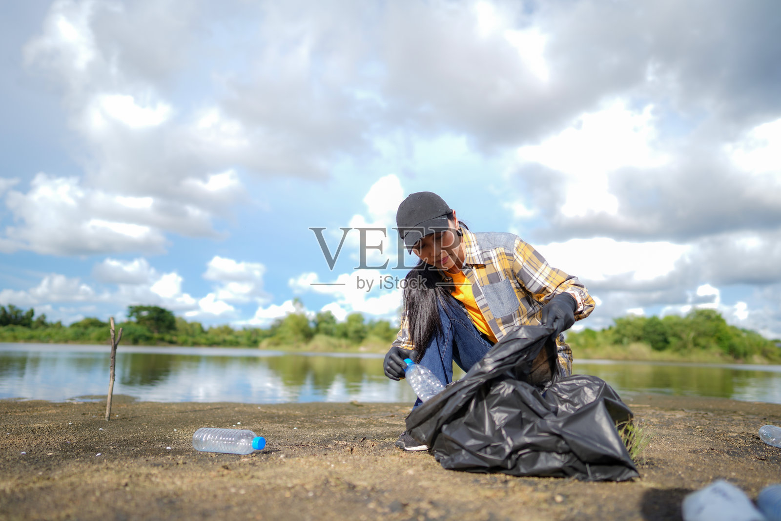一名妇女在海滩上捡垃圾和塑料水瓶照片摄影图片