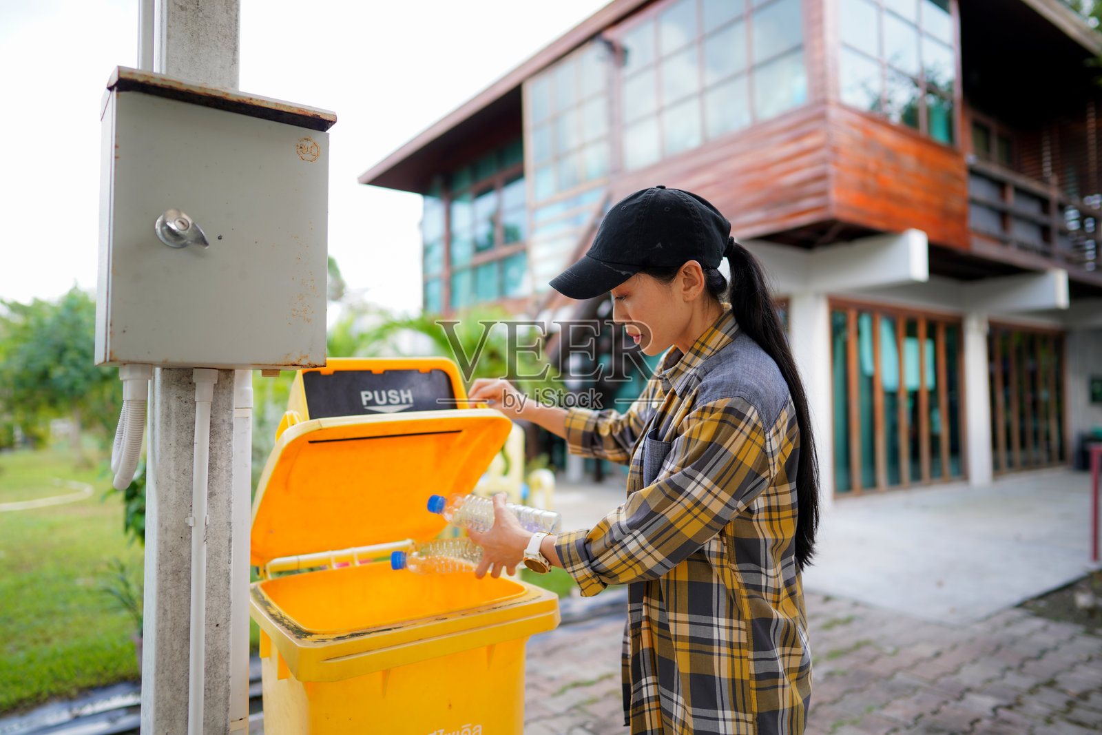 一个女人把塑料瓶扔进回收箱照片摄影图片