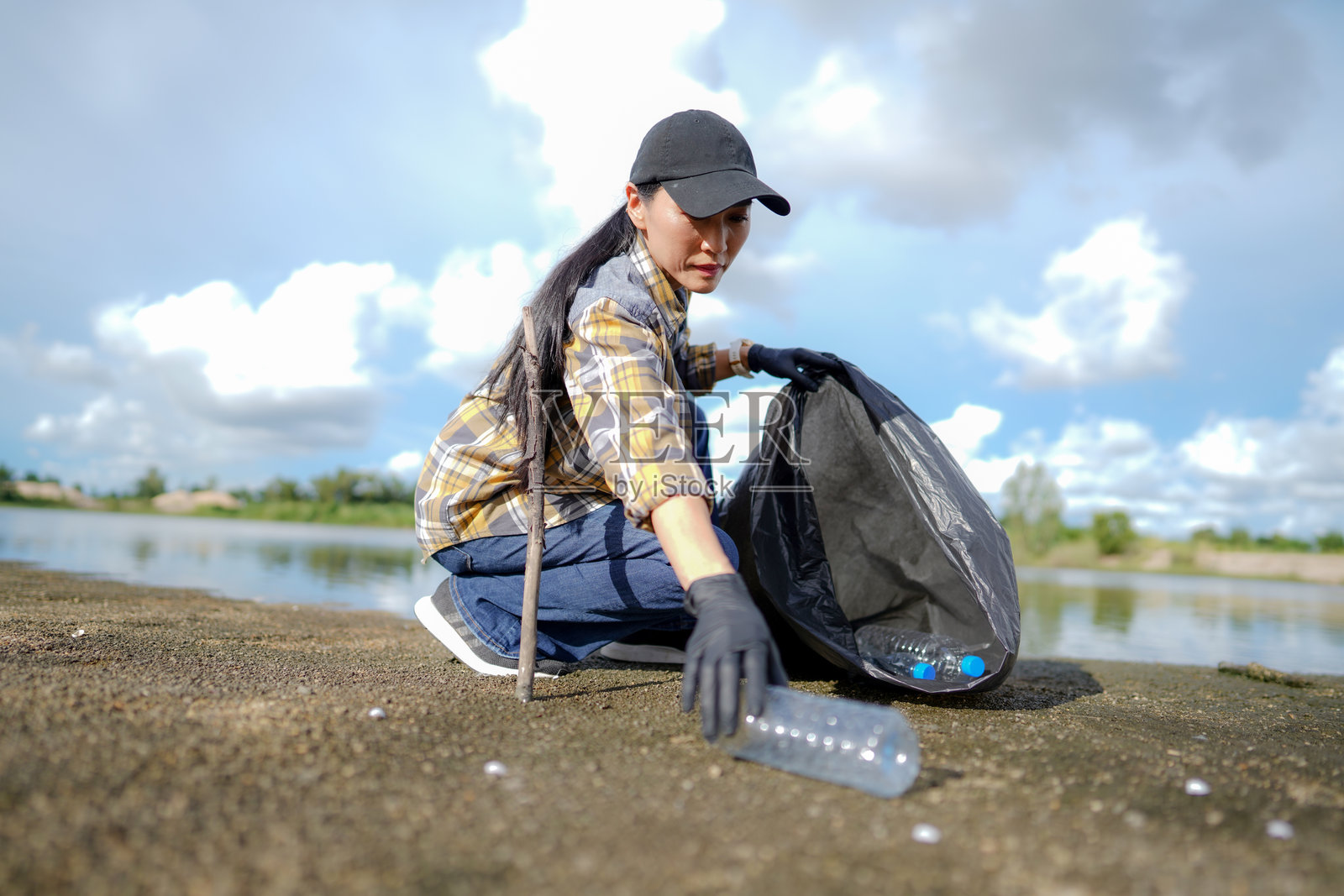 一位女性在海滩上清理垃圾照片摄影图片