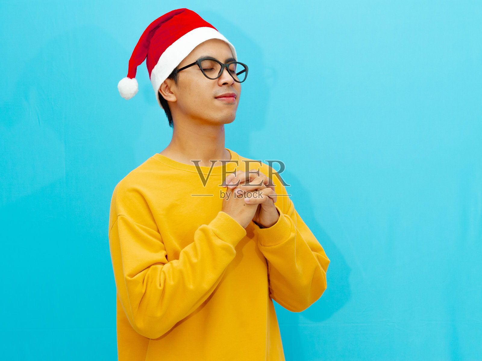 一个戴着圣诞帽的男人在祈祷时微笑照片摄影图片