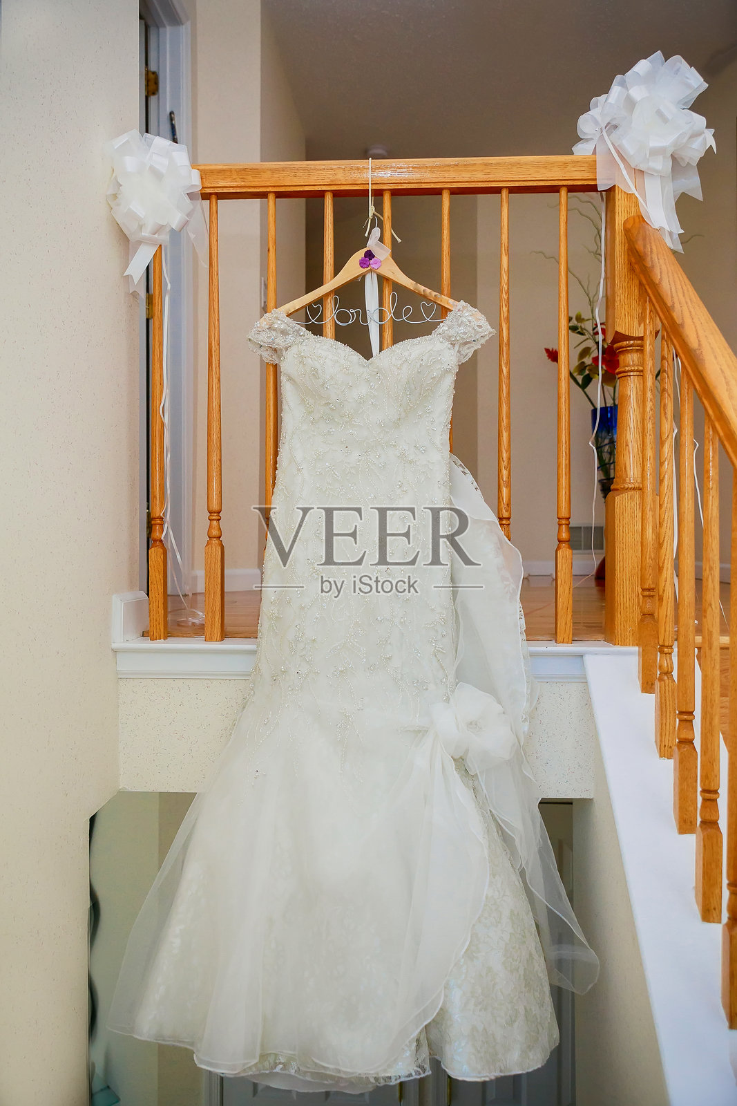 挂在家中栏杆上的白色婚纱照片摄影图片
